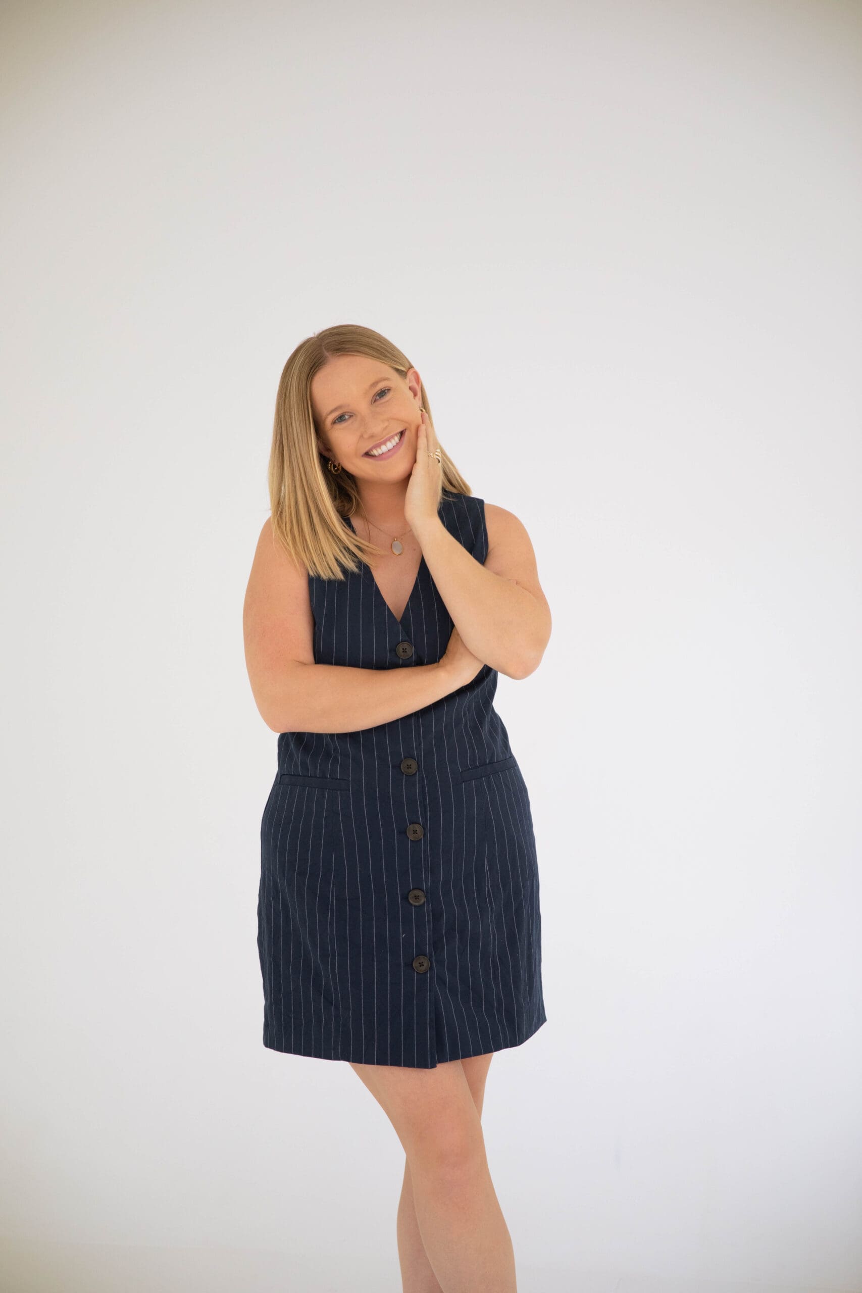 Friendly EMDR therapist smiling in a navy pinstripe dress against a clean white background