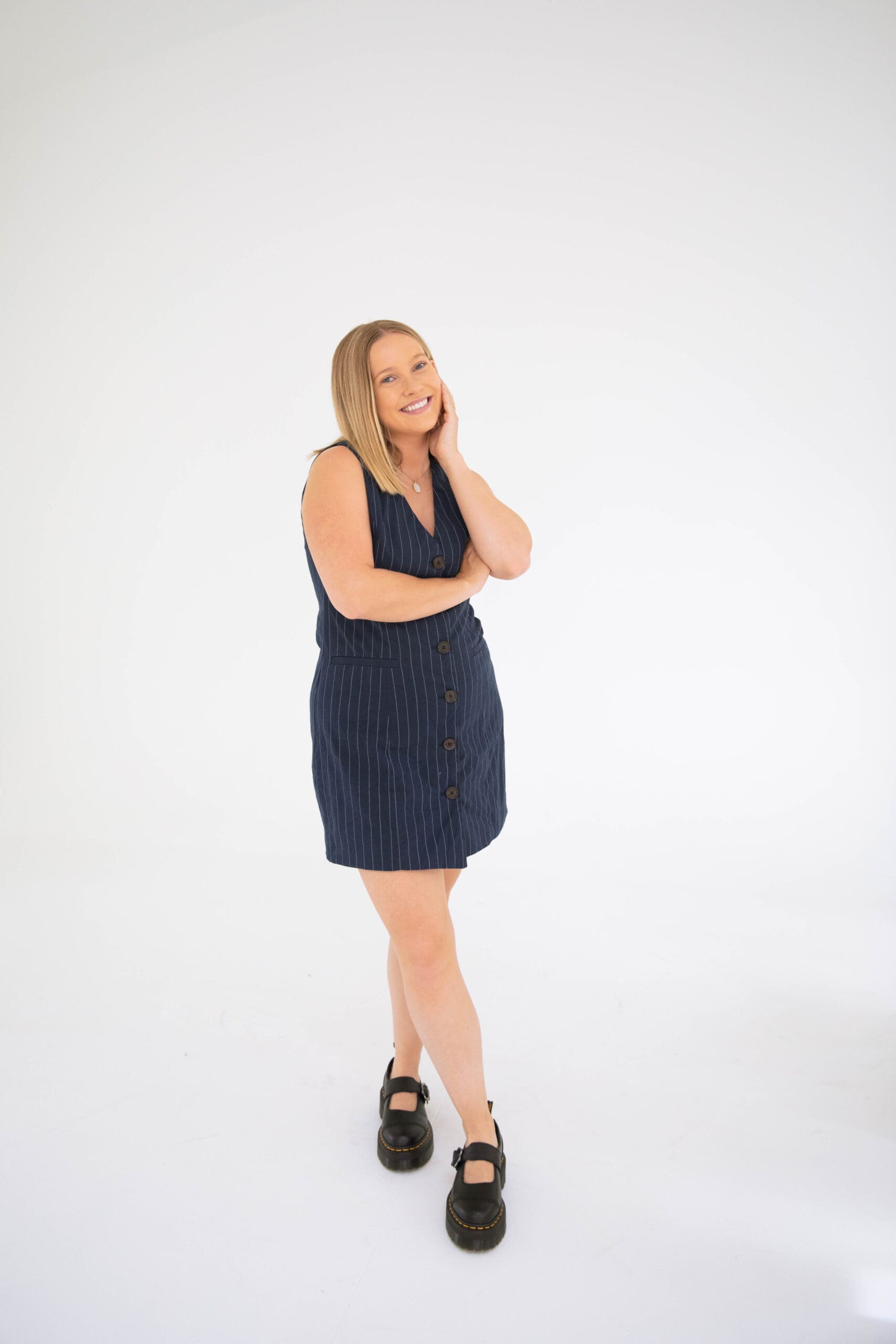 Woman in navy dress posing casually with hand on face, relaxed and approachable EMDR therapist vibe
