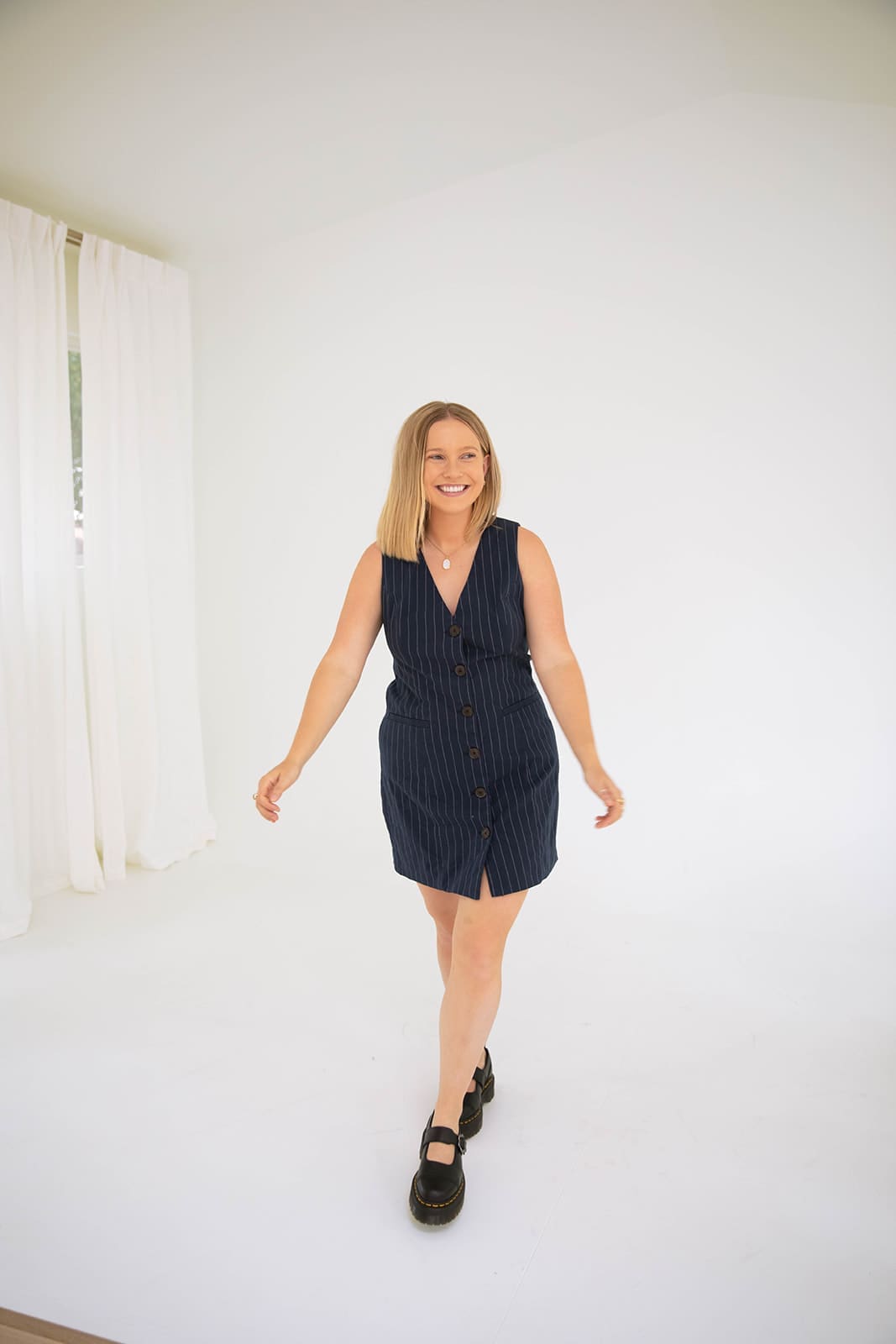 Full-length portrait of a Denver therapist standing laughing as she's walking forward.